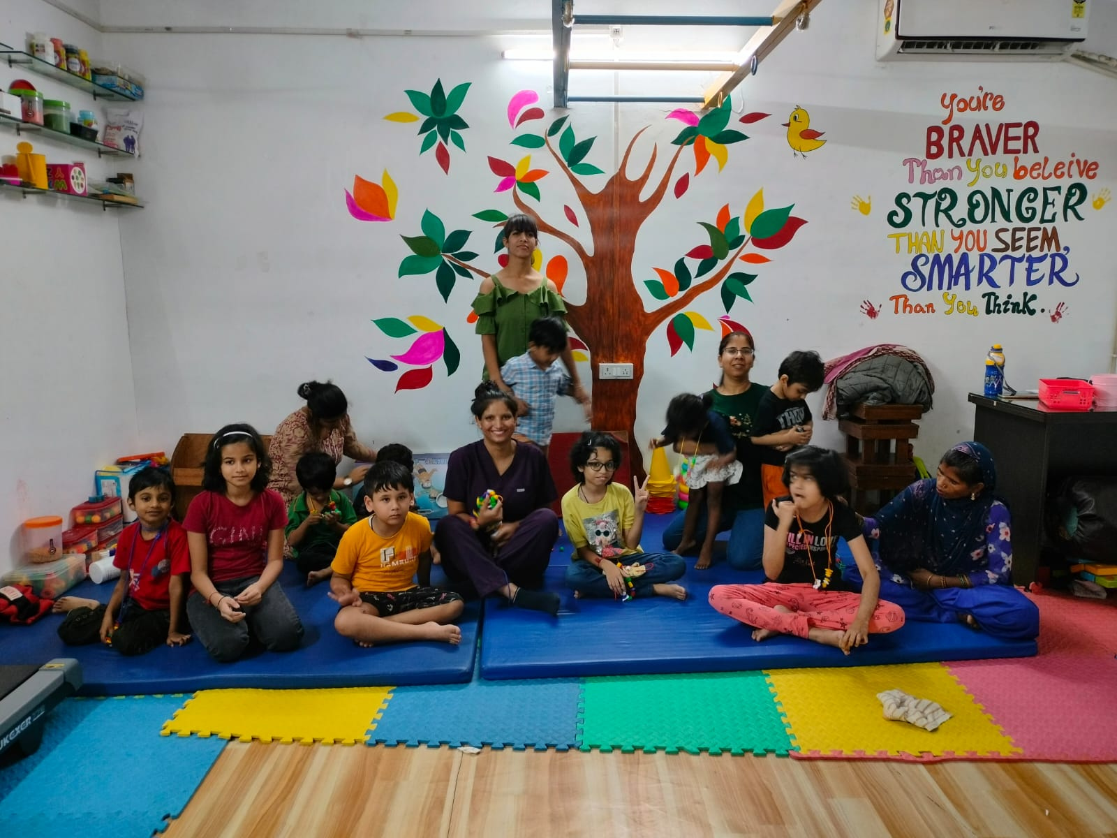 Children and therapists gathered on activity mats at the Centre, beneath a painted tree mural and an encouraging message on the wall.